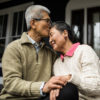 Couple de personnes âgées s'embrassant devant leur maison