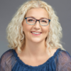 Smiling white woman with curly blond hair wearing glasses