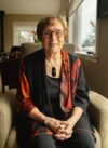 Portrait of Margaret Bayer, an elderly white woman wearing glasses sitting in a living room.