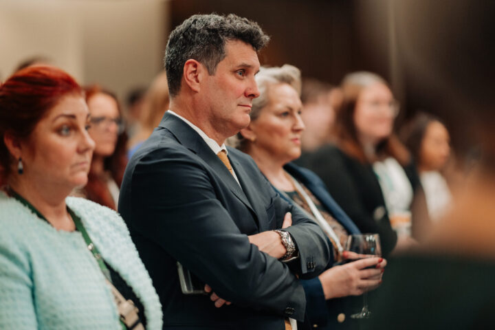 Membres de l'audience écoutant les discours de la réception parlementaire, avec un homme aux cheveux gris foncé en point de mire