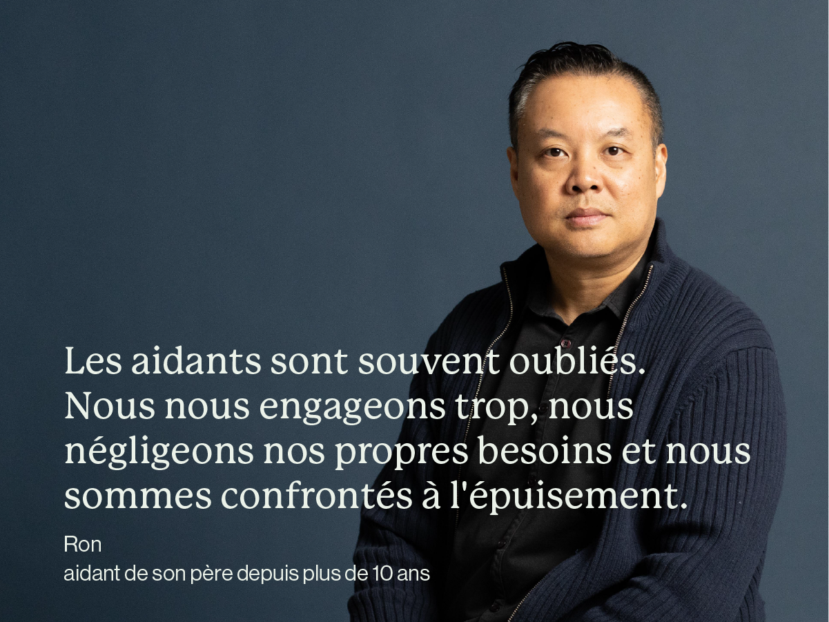 Un homme asiatique debout sur un fond gris. Texte : Les aidants sont souvent oubliés. Nous nous engageons trop, nous négligeons nos propres besoins et nous sommes confrontés à l'épuisement. Ron, aidant de son père depuis plus de 10 ans.