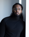 Nicholas Goberdhan, an Indo-Carribean young man with long hair and a beard.