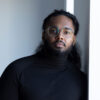 Nicholas Goberdhan, an Indo-Carribean young man with long hair and a beard.