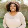 Fredrica Henry-Pottinger, a smiling Black woman with an afro, wearing a cream coloured dress